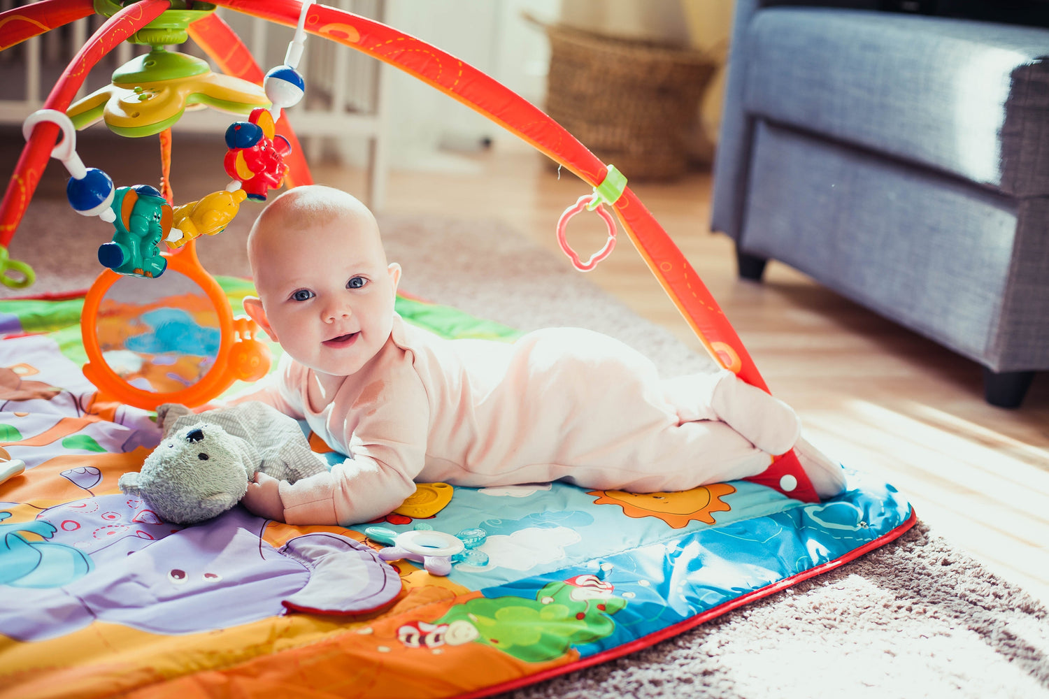 Baby liegt auf einer Babydecke mit Spielzeug und schaut in die Kamera – Produkte für Babys und Kleinkinder (0-2 Jahre)