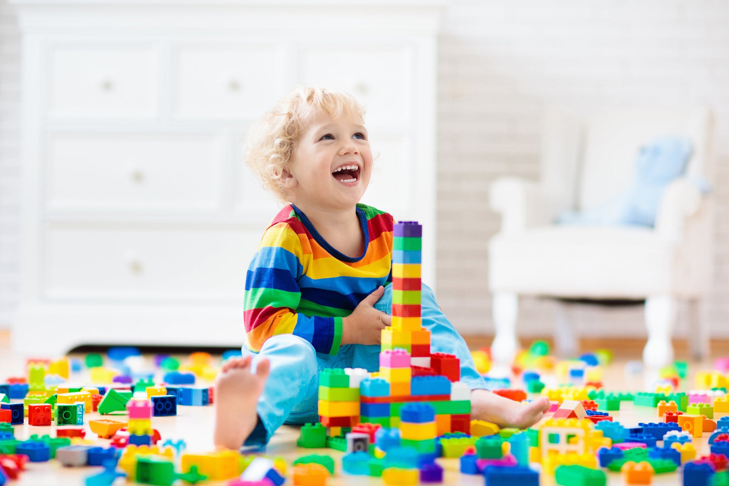Fröhliches Kleinkind spielt auf dem Boden mit Bausteinen – Spielzeug für 2-4 Jahre