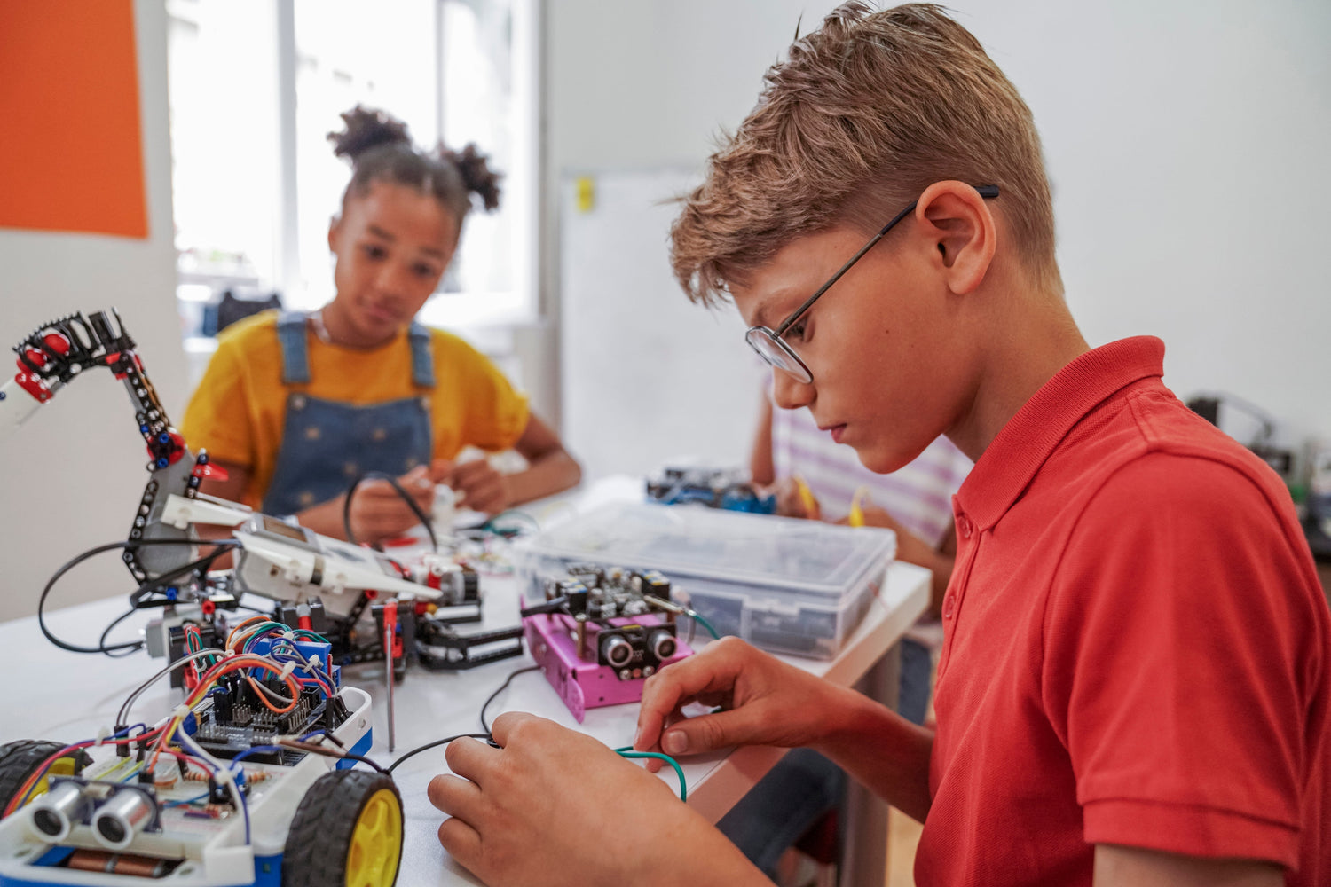 Ältere Kinder (Junge und Mädchen, 8-12 Jahre) am Tisch beim kreativen Basteln von technischem Spielzeug